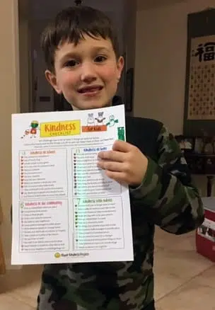 Young Boy Holding His Kindness Checklist To Show How Many Acts Of Kindness He Performed.